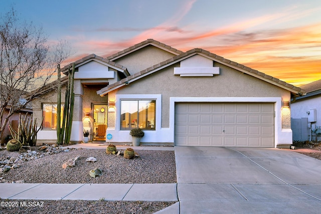 view of front of home with stucco siding, an attached garage, driveway, and a tiled roof