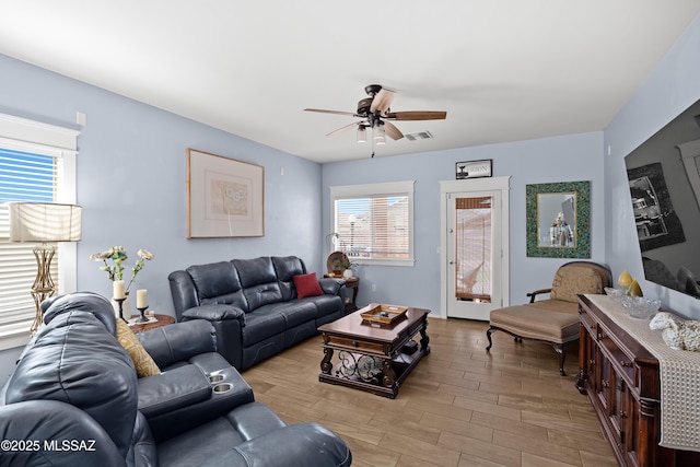 living room with plenty of natural light, visible vents, ceiling fan, and wood finished floors