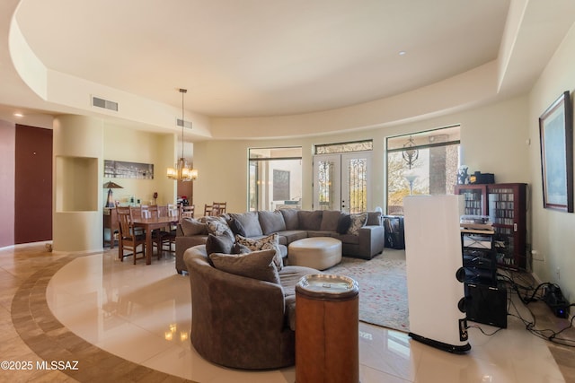 living area featuring a chandelier, a tray ceiling, and visible vents