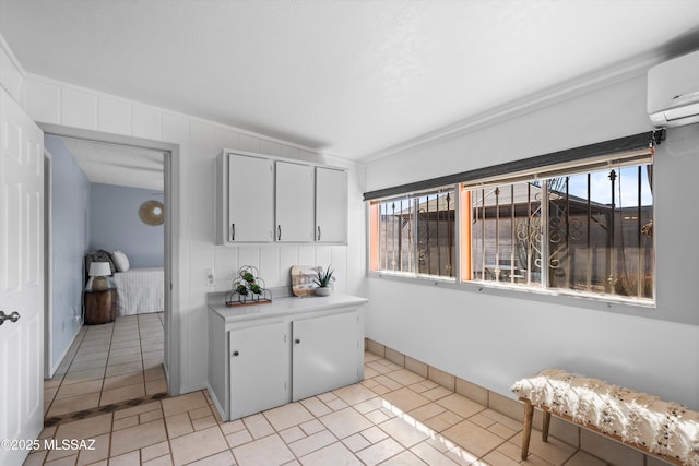 kitchen with a wealth of natural light, an AC wall unit, light tile patterned floors, and light countertops