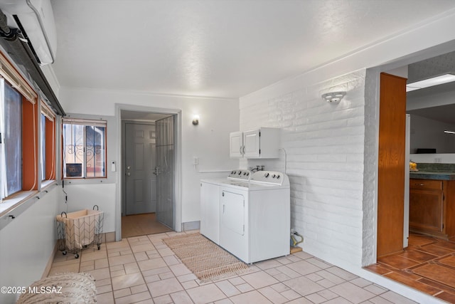 washroom with cabinet space, brick wall, and separate washer and dryer