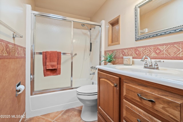 bathroom featuring tile patterned flooring, toilet, vanity, and wainscoting