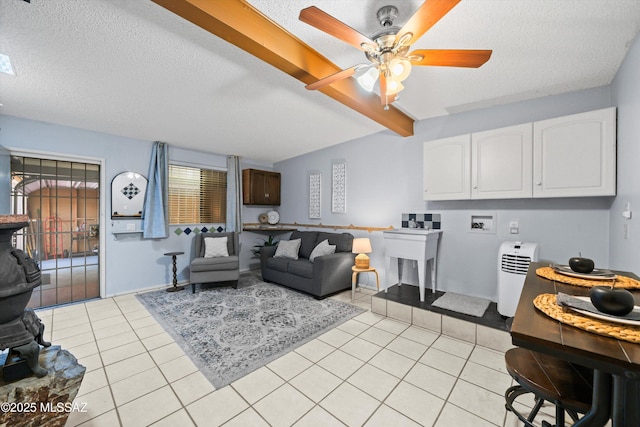 living area featuring ceiling fan, beamed ceiling, light tile patterned floors, and a textured ceiling