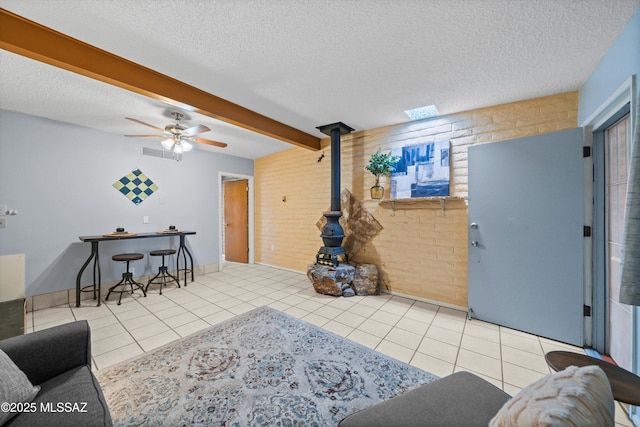 tiled living area with a wood stove, beamed ceiling, visible vents, and a textured ceiling