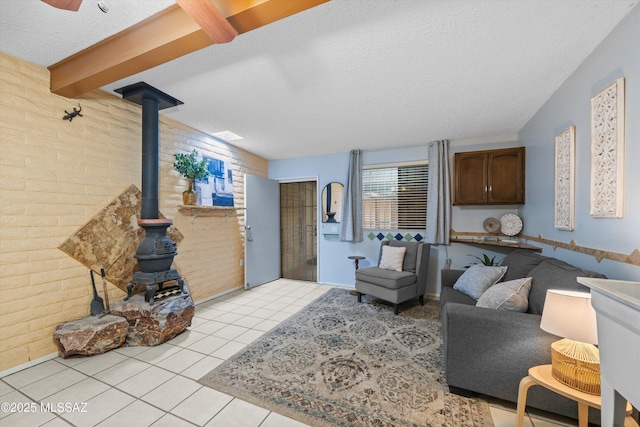 living area with light tile patterned floors, brick wall, beam ceiling, a wood stove, and a textured ceiling