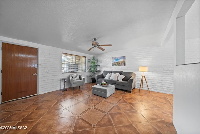 living room with tile patterned floors, a ceiling fan, brick wall, and a textured ceiling