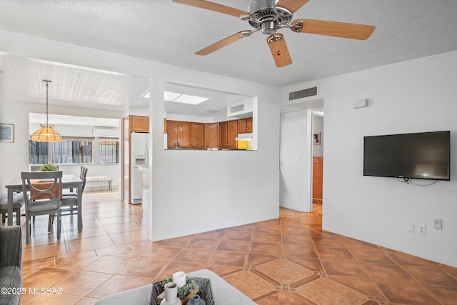 unfurnished living room with light tile patterned floors, visible vents, and ceiling fan