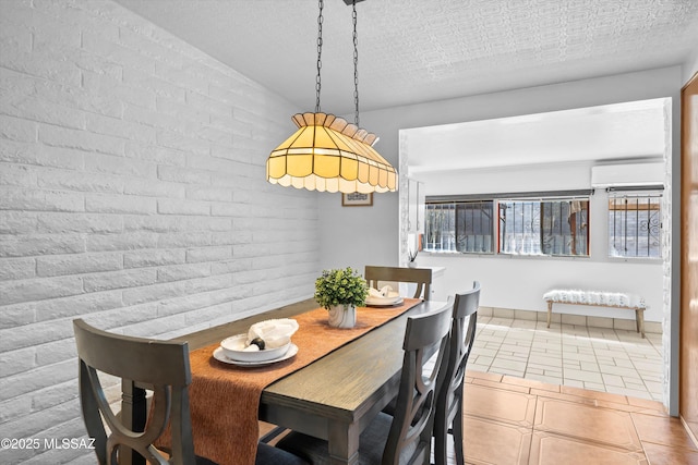 dining space with tile patterned flooring, a textured ceiling, brick wall, and a wall mounted AC