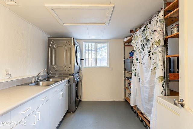 laundry room with stacked washer and dryer, cabinet space, visible vents, a textured wall, and a sink