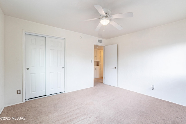 unfurnished bedroom with light colored carpet, a closet, visible vents, and ceiling fan