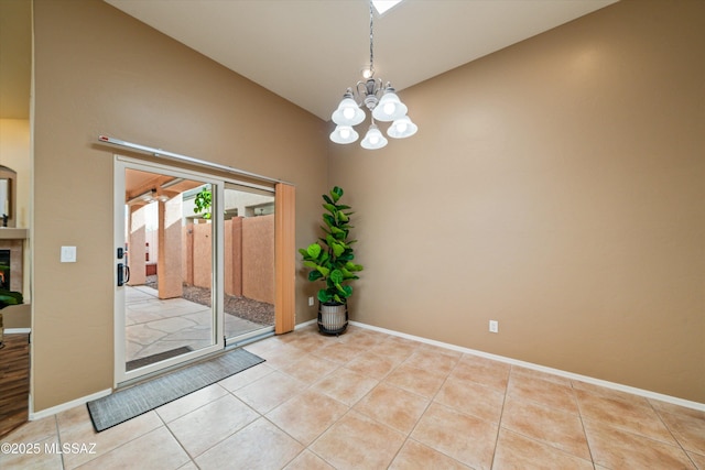 empty room with tile patterned flooring, a chandelier, and baseboards