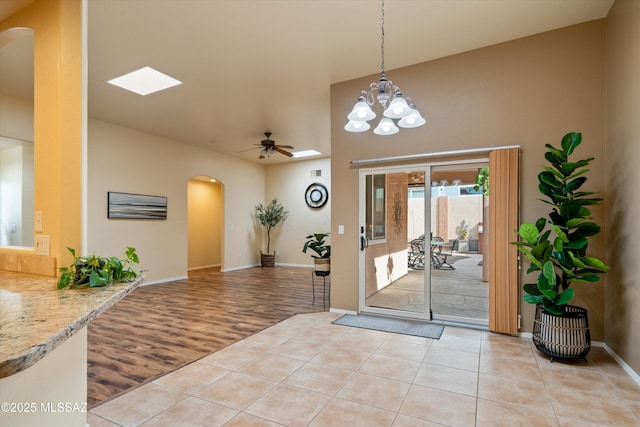 entrance foyer with light tile patterned floors, baseboards, arched walkways, and ceiling fan with notable chandelier