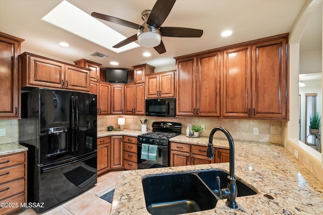 kitchen with visible vents, brown cabinetry, black appliances, a ceiling fan, and a sink