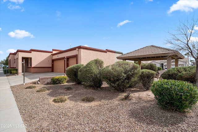 view of front facade with a gazebo, concrete driveway, a garage, and stucco siding