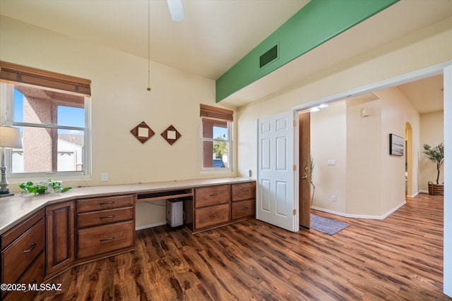 office with visible vents, baseboards, arched walkways, dark wood-style flooring, and built in desk
