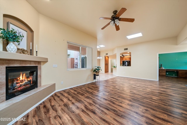 unfurnished living room with ceiling fan, baseboards, wood finished floors, and a fireplace