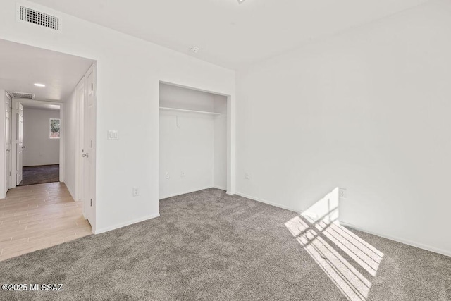 unfurnished bedroom featuring baseboards, visible vents, a closet, and light colored carpet