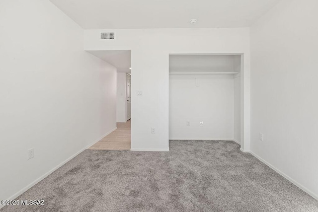 unfurnished bedroom featuring light carpet, baseboards, visible vents, and a closet