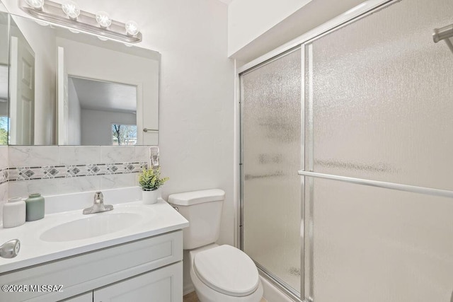 full bath with a shower stall, toilet, vanity, and decorative backsplash