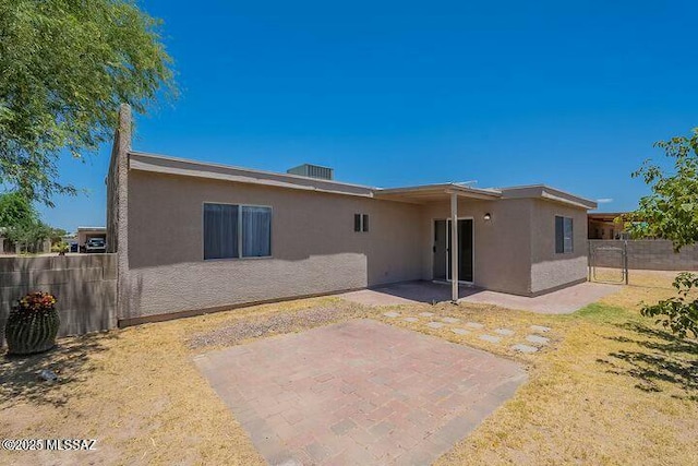 rear view of property featuring a patio area, fence, and stucco siding