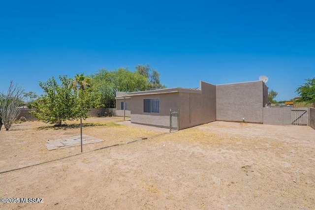 rear view of property with fence and stucco siding