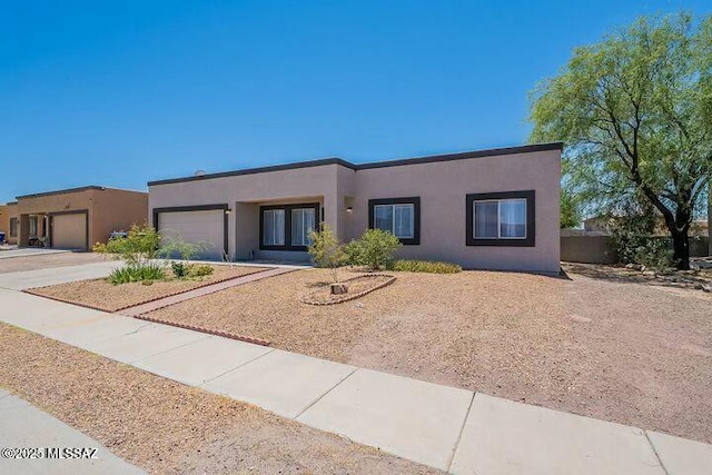 pueblo-style home featuring a garage, driveway, and stucco siding