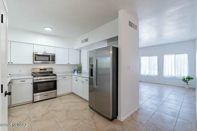 kitchen featuring baseboards, stainless steel appliances, visible vents, and white cabinets