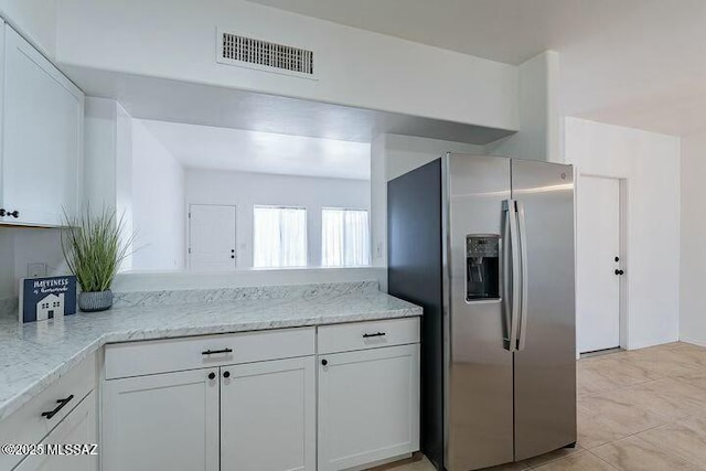 kitchen featuring white cabinets, visible vents, stainless steel refrigerator with ice dispenser, and light stone counters