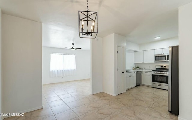 kitchen featuring open floor plan, hanging light fixtures, stainless steel appliances, light countertops, and ceiling fan with notable chandelier