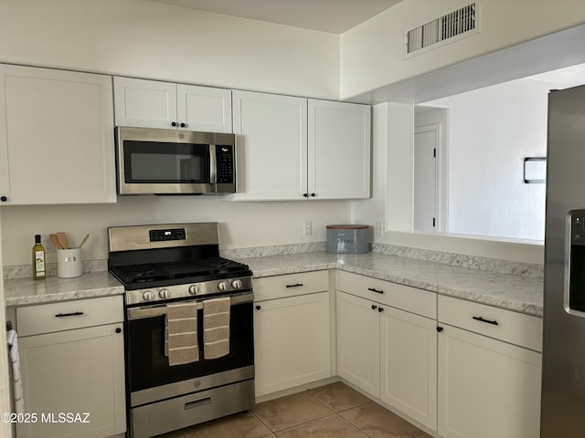 kitchen with stainless steel appliances, light countertops, visible vents, and white cabinets