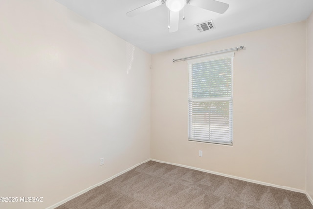 empty room with a ceiling fan, light colored carpet, visible vents, and baseboards