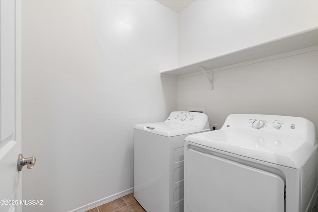 clothes washing area with laundry area, baseboards, washer and dryer, and light tile patterned flooring