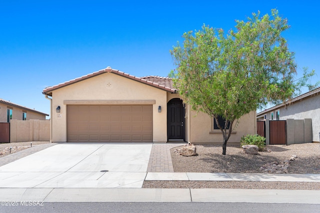 mediterranean / spanish home featuring a garage, fence, driveway, a tiled roof, and stucco siding