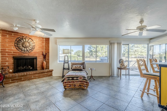 interior space with a ceiling fan, a brick fireplace, a textured ceiling, and baseboards