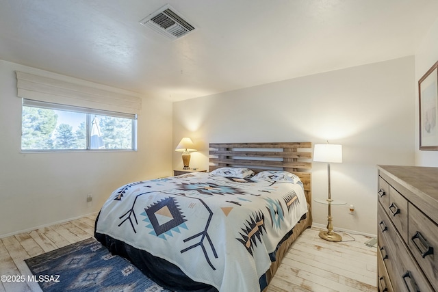 bedroom with light wood-style flooring, visible vents, and baseboards