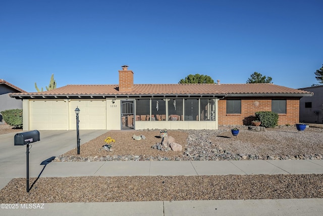 single story home with a tile roof, a chimney, concrete driveway, an attached garage, and a sunroom