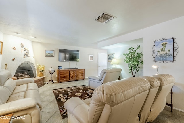 living area featuring a brick fireplace, baseboards, visible vents, and tile patterned floors