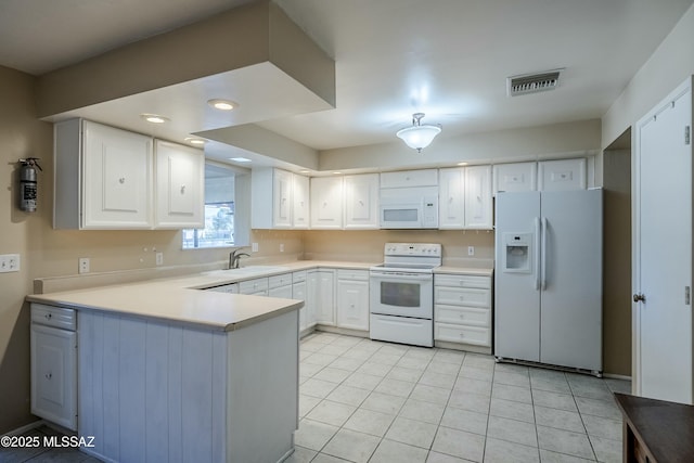 kitchen with white appliances, visible vents, a peninsula, white cabinetry, and a sink