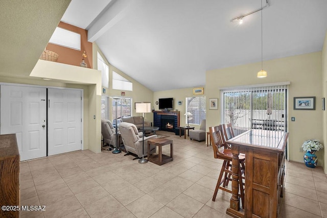 living area with light tile patterned floors, high vaulted ceiling, beamed ceiling, and a brick fireplace