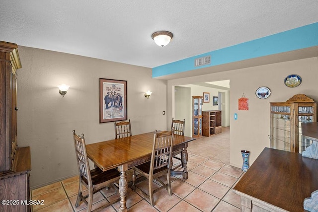 dining space with light tile patterned floors, visible vents, and a textured ceiling