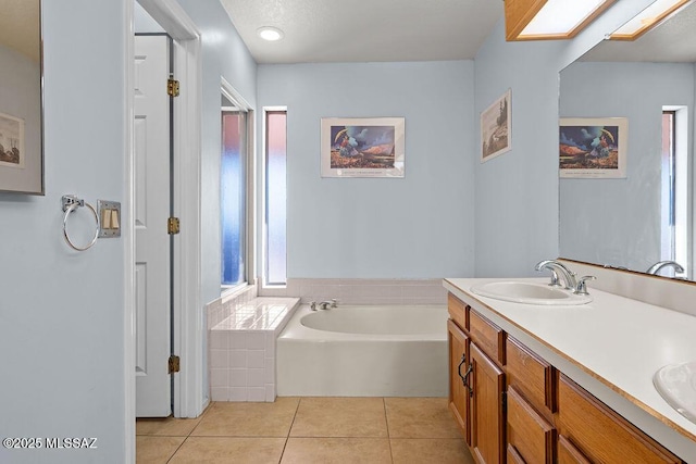 bathroom with a skylight, double vanity, a sink, tile patterned flooring, and a bath