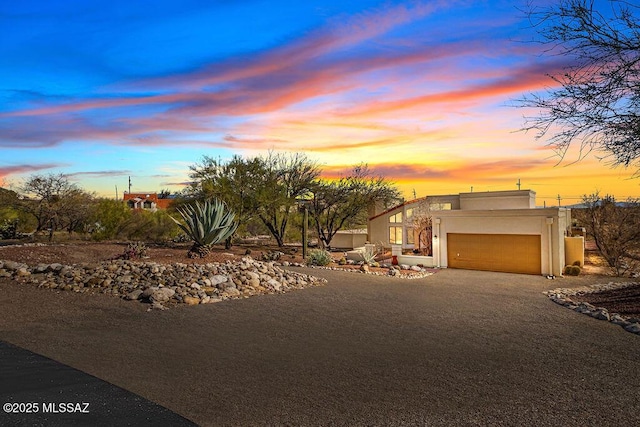 view of front facade with driveway, an attached garage, and stucco siding