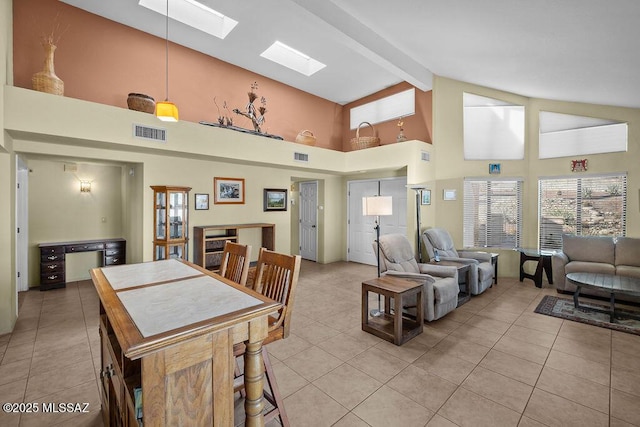 living area with a skylight, beam ceiling, visible vents, and light tile patterned flooring