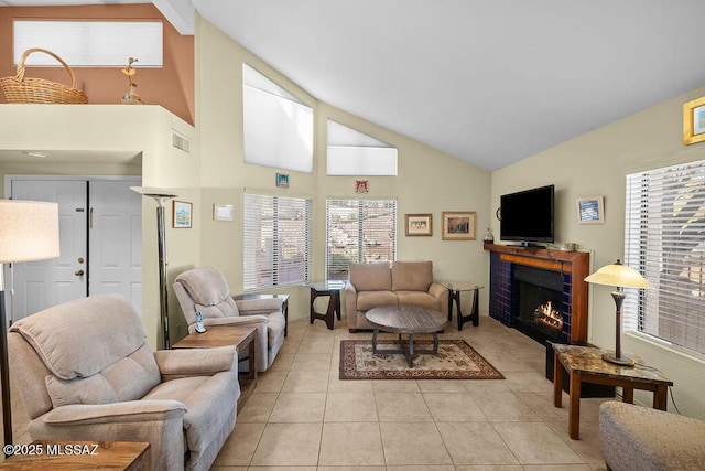 living area with high vaulted ceiling, a brick fireplace, visible vents, and light tile patterned flooring