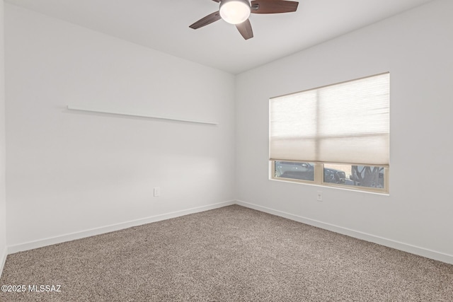 carpeted spare room featuring ceiling fan and baseboards