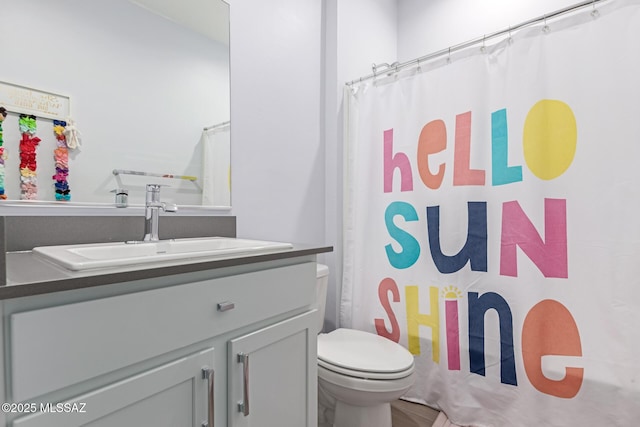 full bath with curtained shower, vanity, and toilet