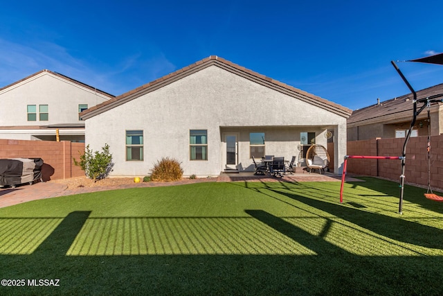 back of property with a patio area, a fenced backyard, a lawn, and stucco siding