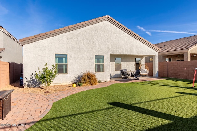 rear view of property with a lawn, a patio, fence, and stucco siding