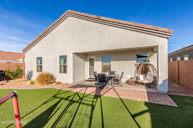 rear view of house with a fenced backyard, a patio, a lawn, and stucco siding