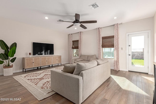 living area with a ceiling fan, recessed lighting, visible vents, and wood finished floors